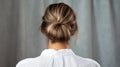 Rear view of young woman elegant bun hairstyle, grey background, copy space