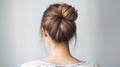 Rear view of young woman elegant bun hairstyle, grey background, copy space