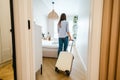 Young woman entering a hotel room with her luggage