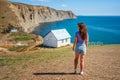 Rear view a young woman in front of a white lonely house on the edge of a cliff with a picturesque mountain landscape and a view Royalty Free Stock Photo