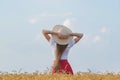 Rear view of young woman with long hair in hat in wheat field. Weekend outsides Royalty Free Stock Photo
