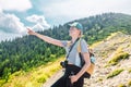 Rear view of a young woman shows the way standing at the edge of a cliff overlooking high mountains. woman looking out Royalty Free Stock Photo