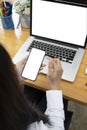 Young woman sitting in front of laptop computer and using mobile phone. Royalty Free Stock Photo