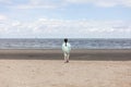 Rear view of a young woman standing on the beach and looking at the sea Royalty Free Stock Photo