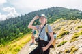 Rear view of a young woman standing at the edge of a cliff overlooking high mountains. woman looking out over an idyllic Royalty Free Stock Photo