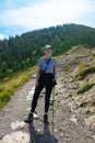 Rear view of a young woman standing at the edge of a cliff overlooking high mountains. woman looking out over an idyllic Royalty Free Stock Photo