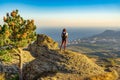 Rear view of young woman standing on mountain cliff and admiring beautiful landscape of coastal town in mountainous area. Teen Royalty Free Stock Photo