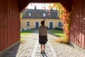 Rear view of young woman standing in wooden entrance of elegant suburban house