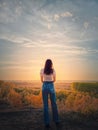 Rear view of a young woman on te top of a hill admiring the calm sunset over the autumn valley with colorful trees. Fall season Royalty Free Stock Photo