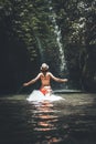 Rear view of young woman tourist running in the river in the deep jungle with waterfall. Real adventure concept. Bali Royalty Free Stock Photo