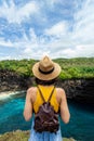 Rear view of young woman traveler standing on cliff looking at Broken Beach Nusa Penida Bali. Summer vacation. Vertical. Royalty Free Stock Photo