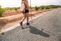 Rear view of young woman walking on the road. Concept of hiking tourism. Shadow silhouette walking