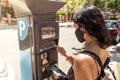 Rear view of young woman wearing facial mask and using payment machine on the street to park Royalty Free Stock Photo