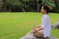 Rear view of young yogi man doing yoga meditation while sitting in lotus position on the rock in the park. Left black for message Royalty Free Stock Photo