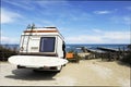 Rear of vintage camper parked on the beach seaside with a surfboard on back - Leisure trip in the summer