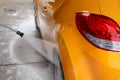 Rear wheel and back of yellow car being washed with jet water st Royalty Free Stock Photo