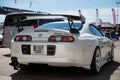 Rear of a white fourth-generation Toyota Supra with a carbon fiber spoiler parked on a street