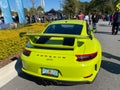 The rearend of a bright green Porsche GT3 at a free car show in a retail store parking lot