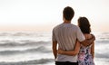 Loving young couple looking out at the ocean at sunset Royalty Free Stock Photo