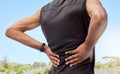 Rearview of athlete with back pain. Closeup back view of an uncomfortable young sportsman standing on a sport field