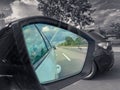 Rearview car driving mirror view at a colorful rainbow while the surrounding is black and white, kind of colorkey.