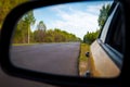 Rearview car driving mirror view forest road Royalty Free Stock Photo