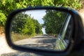 Rearview car driving mirror view green forest and village road. Royalty Free Stock Photo