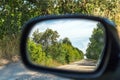 Rearview car driving mirror view green forest and village road Royalty Free Stock Photo