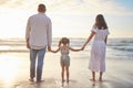 Rearview cute mixed race girl standing hand in hand with her mom and dad in the sea at the beach. A young couple and Royalty Free Stock Photo