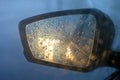 Rearview mirror with drops of water from the rain and a car with headlights. Selective focus, shallow DOF Royalty Free Stock Photo