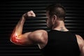 Pain is just a part of the package. Rearview shot of an athletic young man flexing with an elbow injury in the studio. Royalty Free Stock Photo