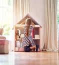 She's a little homemaker. Rearview shot of a little girl playing with her dollhouse while sitting on her bedroom