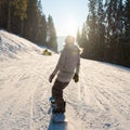 Rearview shot of a snowboarder riding the slope in the mountains on a beautiful winter sunny day Royalty Free Stock Photo