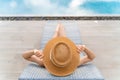 Rearview of woman in sun hat relaxing at luxury hotel tropical resort swimming pool Royalty Free Stock Photo