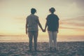 Young lesbian couple holding hands watching a beach sunset Royalty Free Stock Photo