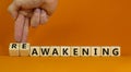 Businessman turns cubes and changes the word \'awakening\' to \'reawakening\'. Beautiful orange background  co Royalty Free Stock Photo