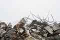 The rebar sticking up from piles of brick rubble, stone and concrete rubble against the sky in a haze