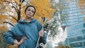 Rebellious young caucasian woman with skateboard standing under the tree with yellow leaves in city park in autumn