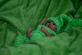 Reborn baby doll, in green dress, green background