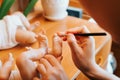 Reborning, creation of craft realistic toys, hobby concept. Close-up of female craftsman decorating with painting brush