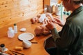 Reborning, handmade newborn baby doll, hobby, craft concept. Young female craftsman sitting with realistic child toy at table