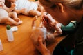 Reborning hobby and craft. Young female master reborn maker decorating realistic newborn baby doll while sitting in workshop