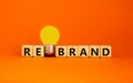 Rebrand symbol. Wooden cubes with word `rebrand`. Yellow light bulb. Beautiful orange background. Business and rebrand concept. Royalty Free Stock Photo