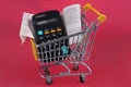 French cash receipt in supermarket trolley with calculator on red background