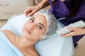 Receiving electric darsonval facial massage procedure at beauty salon. Royalty Free Stock Photo