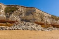 A rock fall of white chalk partially obscures the red and orange stratified layers on the cliffs of Old Hunstanton, Norfolk, UK Royalty Free Stock Photo