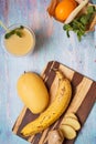 Recepie of healthy fresh yellow fruit mango smoothie at blue table Royalty Free Stock Photo