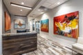 Reception area featuring a sleek desk and paintings hanging on the wall, A reception area with a sleek desk and modern artwork on