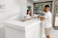 At reception desk beautiful medical assistant giving some blank information to the patient to signed before go to the Royalty Free Stock Photo