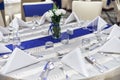 Reception dinner table setup with dinnerware, napkin, spoon, fork and glasses decoration with blue sash cloth stripe